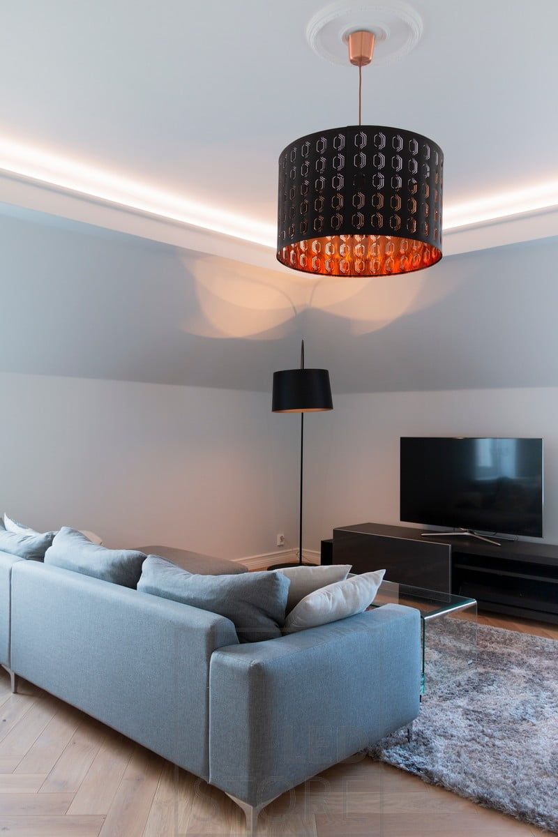 In the living room, a ceiling-mounted, indirect lighting system. The lighting is atmospheric and soft, without glare.